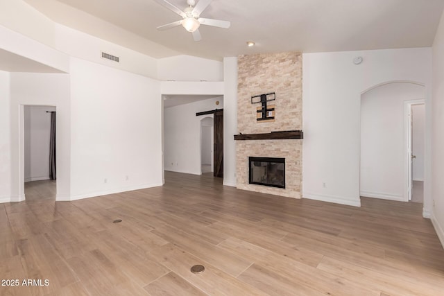 1213 W Beck Ln, Phoenix, AZ 85023 - unfurnished living room featuring ceiling fan, a barn door, a fireplace, arched walkways, and vaulted ceiling