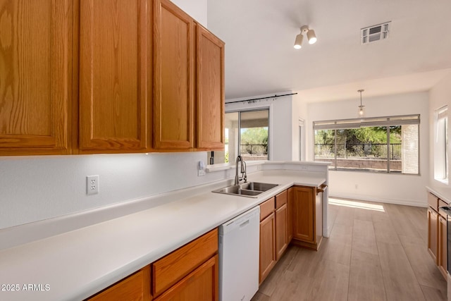 1213 W Beck Ln, Phoenix, AZ 85023 - kitchen featuring dishwasher, light countertops, brown cabinets, light wood-type flooring, and pendant lighting