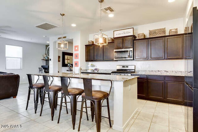 kitchen featuring stainless steel appliances, open floor plan, visible vents, and a breakfast bar