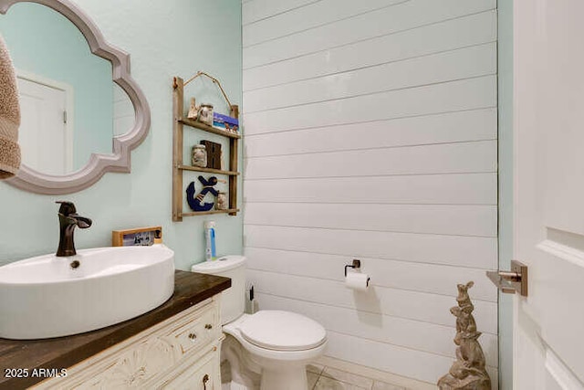 half bathroom featuring toilet, vanity, and tile patterned flooring