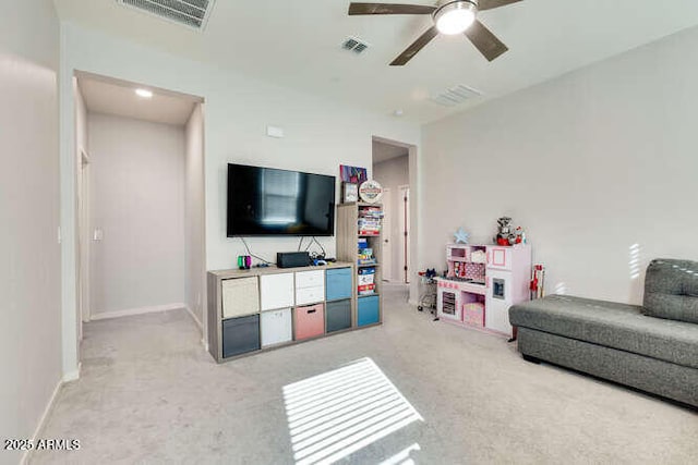 living area featuring baseboards, light colored carpet, visible vents, and ceiling fan