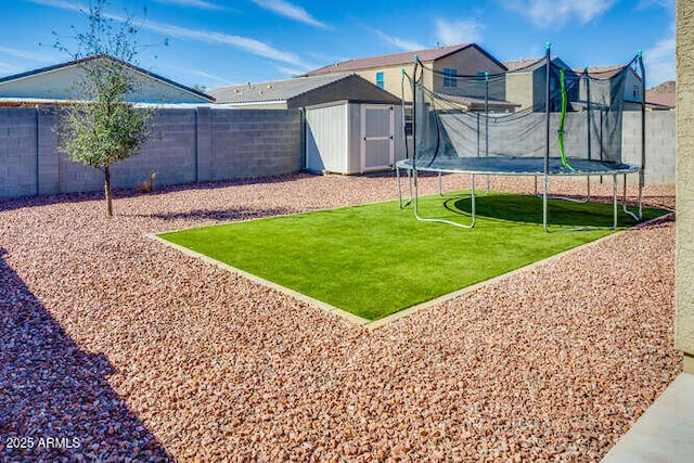 view of playground featuring an outbuilding, a fenced backyard, a storage unit, a trampoline, and a lawn