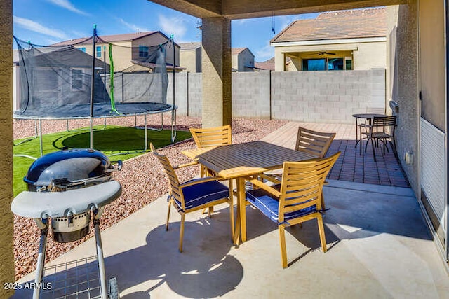 view of patio / terrace featuring a fenced backyard, outdoor dining area, and a trampoline