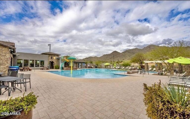 community pool with a mountain view and a patio