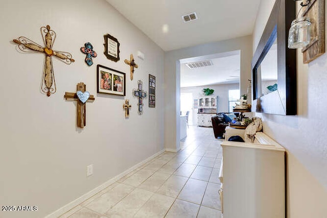 hall featuring light tile patterned floors, visible vents, and baseboards