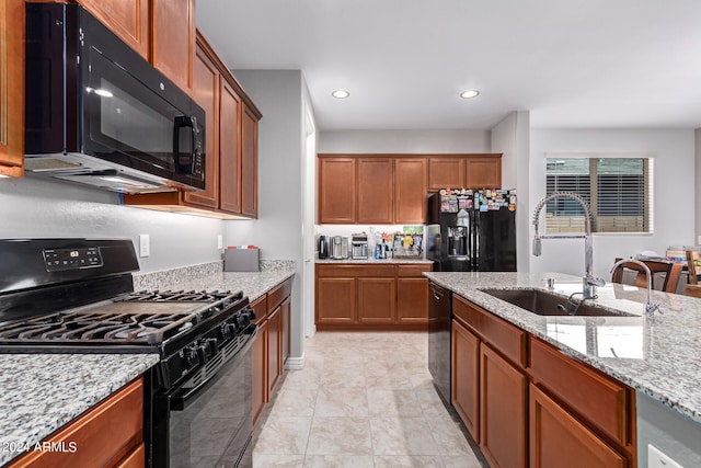 kitchen featuring light stone countertops, light tile patterned flooring, black appliances, and sink