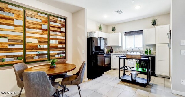 kitchen with black appliances, light tile patterned flooring, and white cabinets