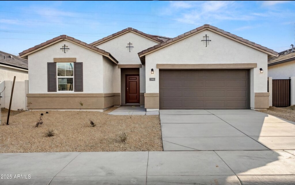 view of front of home with fence, driveway, an attached garage, stucco siding, and a tiled roof