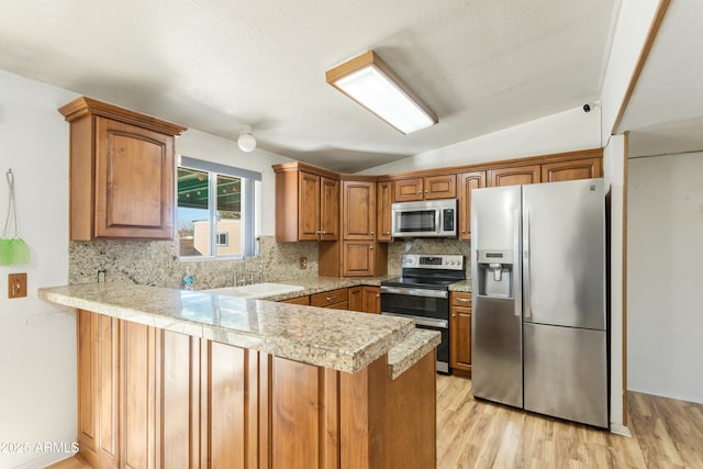 kitchen featuring vaulted ceiling, appliances with stainless steel finishes, kitchen peninsula, and sink