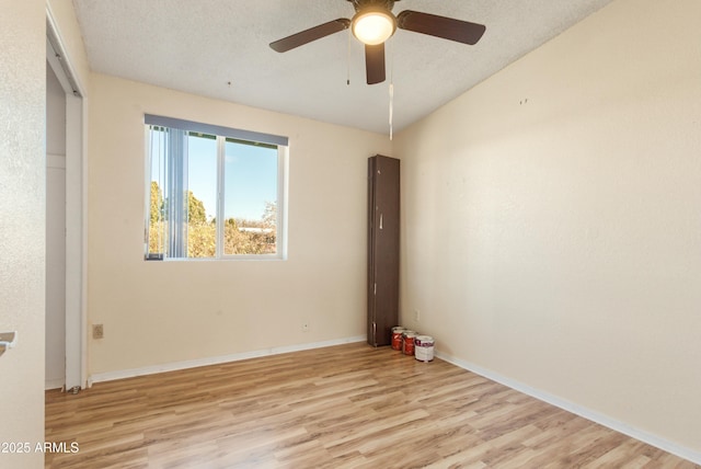 empty room with ceiling fan, a textured ceiling, and light wood-type flooring