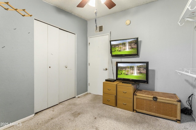 bedroom featuring ceiling fan, light colored carpet, a textured ceiling, and a closet