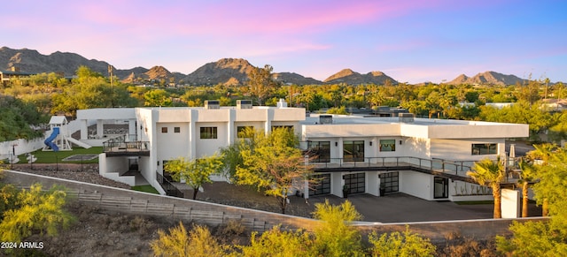 back house at dusk featuring a garage and a mountain view