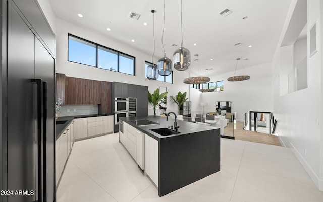 kitchen with a towering ceiling, appliances with stainless steel finishes, sink, and tasteful backsplash