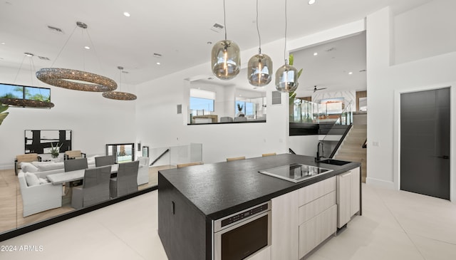 kitchen featuring black electric stovetop, stainless steel oven, a kitchen island, light tile floors, and sink