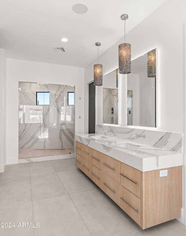 bathroom with tile floors, dual sinks, vanity with extensive cabinet space, and tiled shower