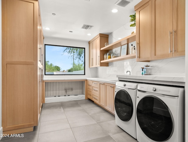 laundry area featuring separate washer and dryer, cabinets, and light tile floors