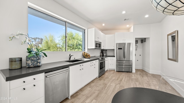 kitchen featuring white cabinets, appliances with stainless steel finishes, sink, and light hardwood / wood-style floors