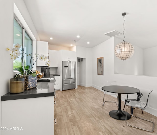 kitchen with stainless steel fridge, light wood-type flooring, pendant lighting, sink, and white cabinetry