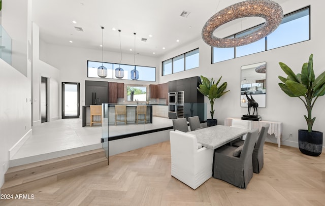 dining room with a towering ceiling, light parquet floors, and sink