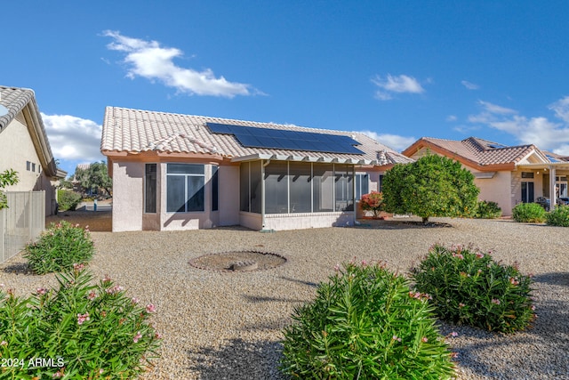 back of property featuring a sunroom and solar panels