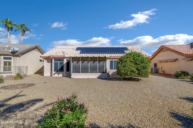 back of property with solar panels, cooling unit, and a sunroom