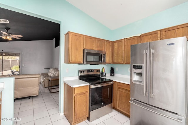 kitchen with lofted ceiling, light tile patterned floors, stainless steel appliances, and ceiling fan