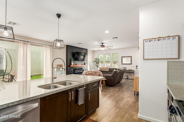 13380 N 148th Ave, Surprise, AZ 85379 - kitchen featuring a sink, dishwasher, light wood-style floors, dark brown cabinetry, and pendant lighting