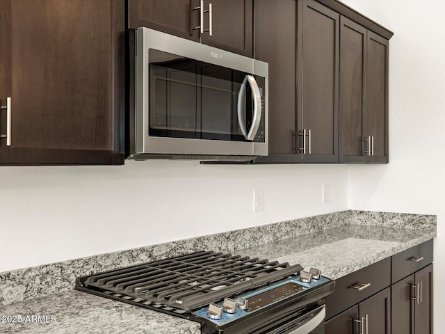 kitchen with gas stove, light stone countertops, and dark brown cabinets