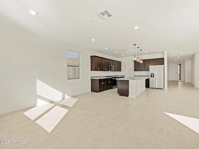 kitchen featuring pendant lighting, appliances with stainless steel finishes, a kitchen island with sink, and dark brown cabinets