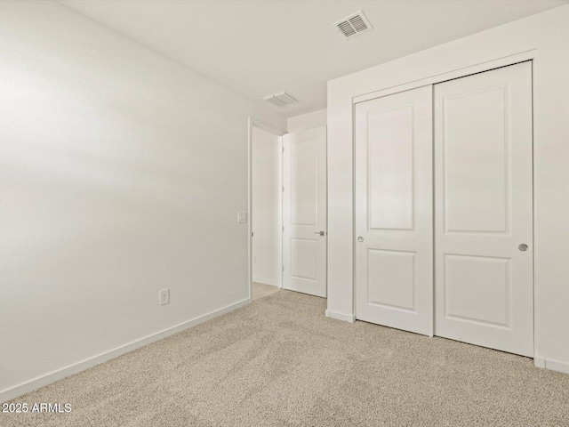 unfurnished bedroom with light carpet and a closet