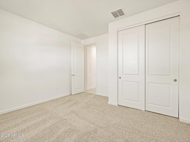 unfurnished bedroom featuring light colored carpet and a closet