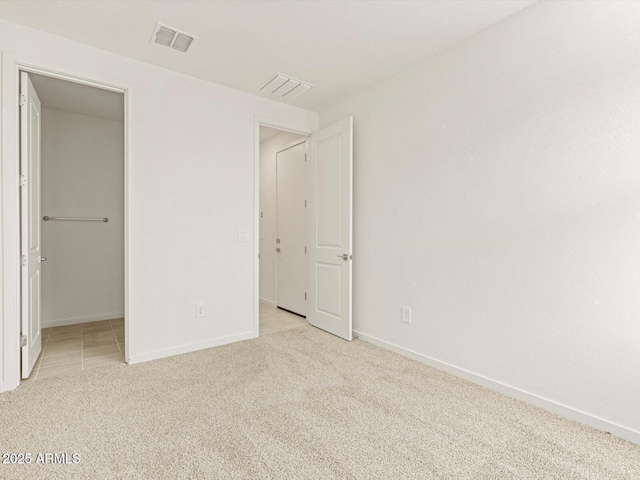 unfurnished bedroom featuring light colored carpet and a walk in closet