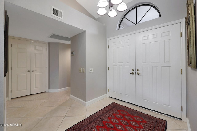 entryway with light tile patterned flooring, vaulted ceiling, and a chandelier