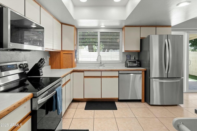 kitchen with light countertops, a sink, light tile patterned floors, and appliances with stainless steel finishes