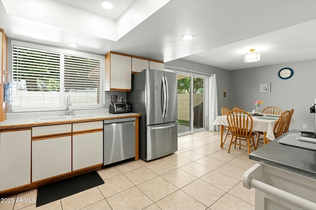 kitchen with a sink, light countertops, appliances with stainless steel finishes, and light tile patterned floors