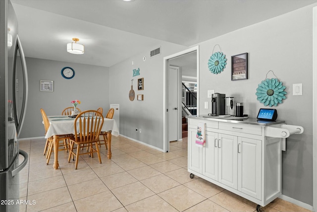 dining space featuring baseboards, visible vents, stairway, and light tile patterned floors