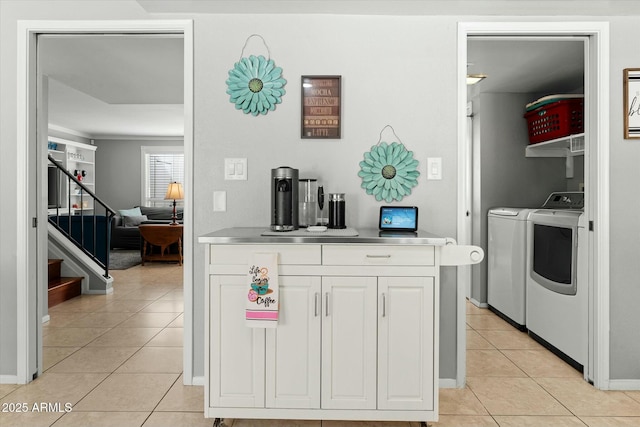 kitchen with white cabinetry, stainless steel countertops, washer and clothes dryer, and light tile patterned floors