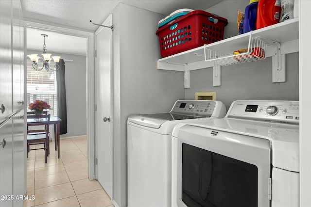 clothes washing area with light tile patterned floors, an inviting chandelier, laundry area, and washer and clothes dryer