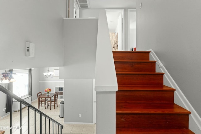 staircase featuring tile patterned flooring, ceiling fan with notable chandelier, baseboards, and visible vents