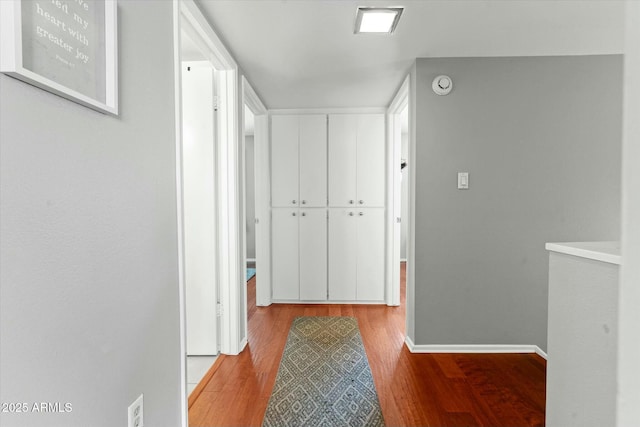 corridor with baseboards and wood finished floors