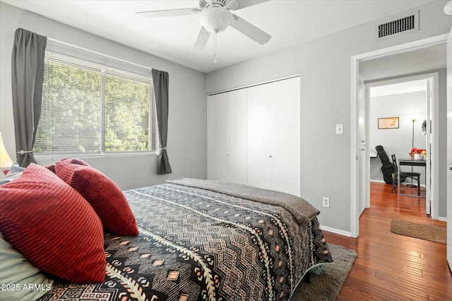 bedroom with a closet, visible vents, baseboards, a ceiling fan, and wood-type flooring