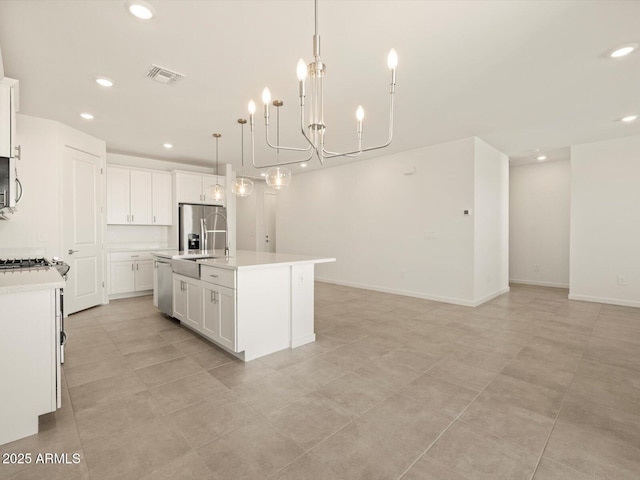 kitchen with a chandelier, decorative light fixtures, stainless steel appliances, a center island with sink, and white cabinets