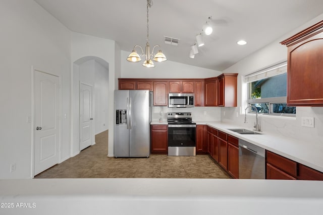 kitchen featuring vaulted ceiling, decorative light fixtures, tasteful backsplash, sink, and stainless steel appliances