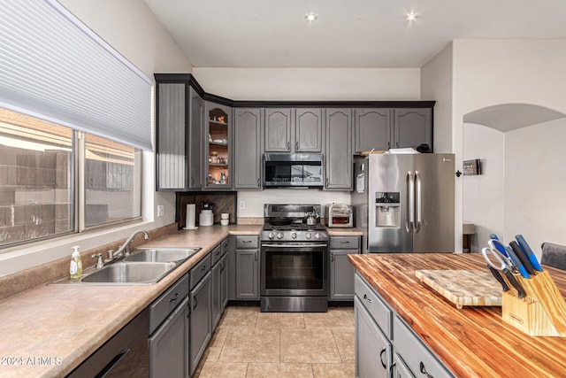 kitchen featuring appliances with stainless steel finishes, butcher block countertops, sink, and gray cabinets