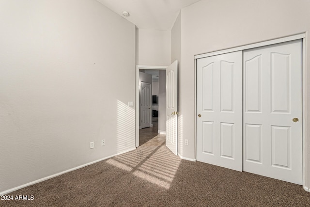 unfurnished bedroom featuring dark carpet and a closet