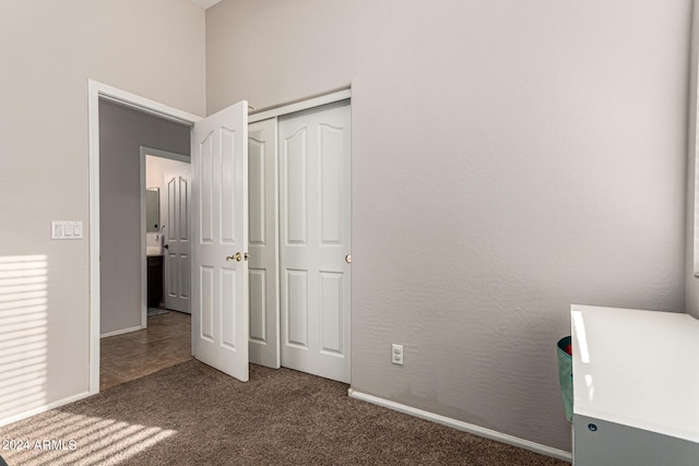 unfurnished bedroom with dark carpet and a closet