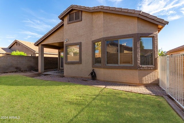 rear view of property with a lawn and a patio