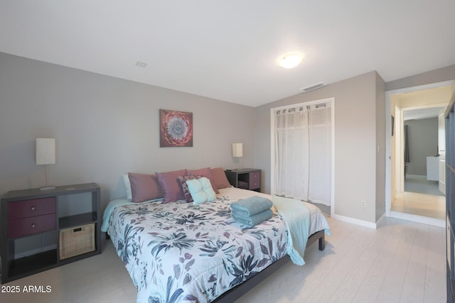 bedroom featuring visible vents, wood finished floors, a closet, baseboards, and vaulted ceiling