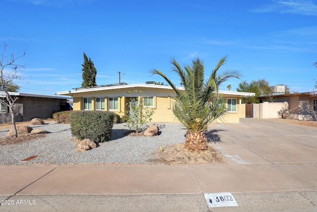 view of front of house featuring stucco siding, driveway, and fence