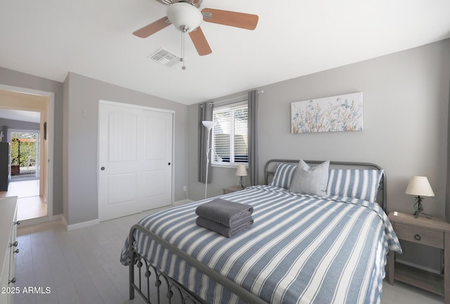 bedroom featuring visible vents, ceiling fan, vaulted ceiling, light wood-style flooring, and a closet